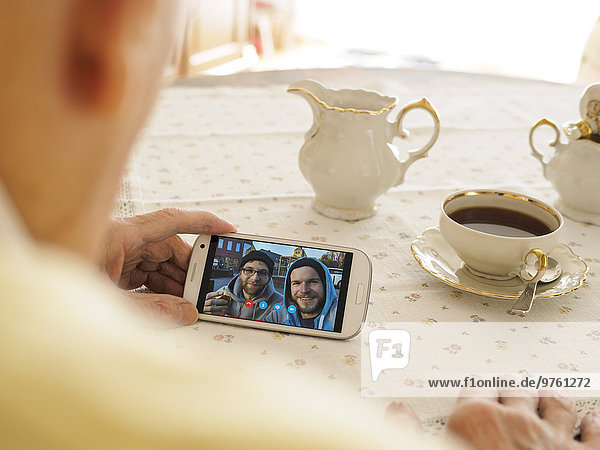 Grandfather videoconferencing with grandson and friend via smartphone