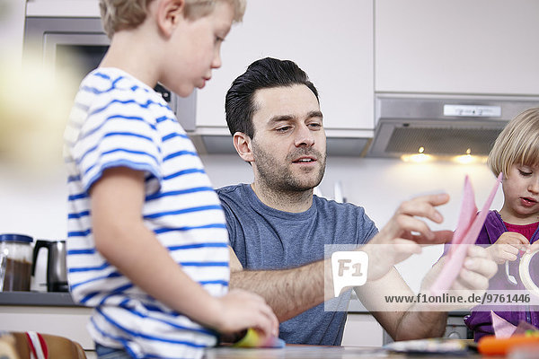 Father tinkering in kitchen with son and daughter