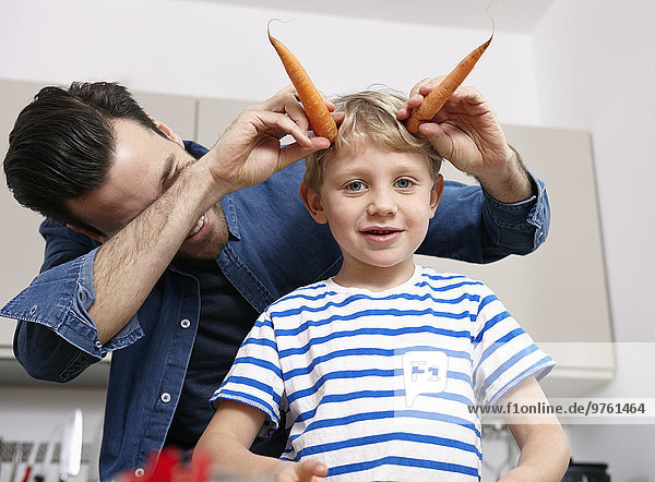 Father playin with kids in kitchen  making carrot horns