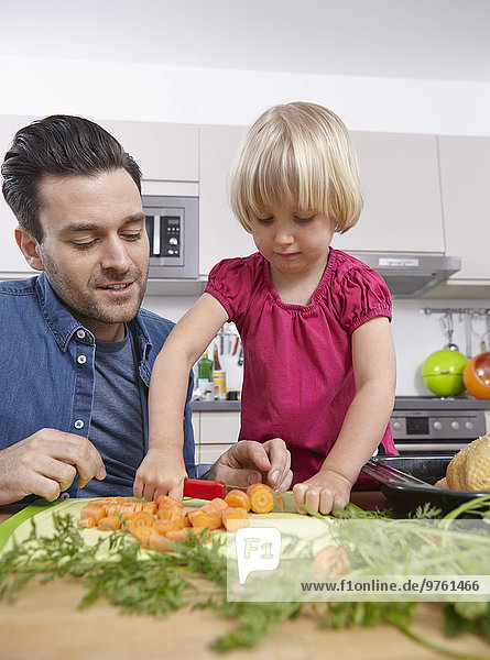 Father preparing food in kitchen with daughter