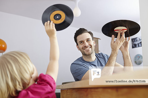 Father showing old vinyl records to daughter
