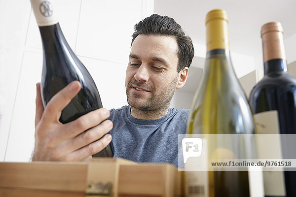 Man at home looking at wine bottles