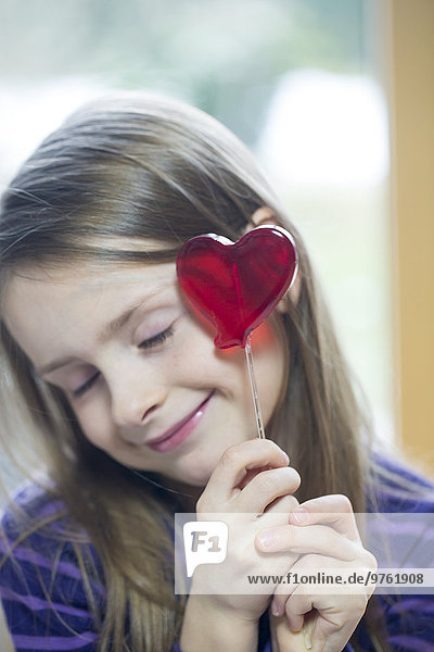 Girl holding heart-shaped lollipop
