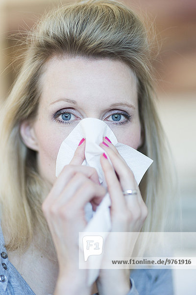 Blond woman blowing nose