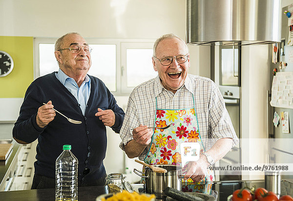 Zwei glückliche Senior-Freunde beim Kochen in der Küche