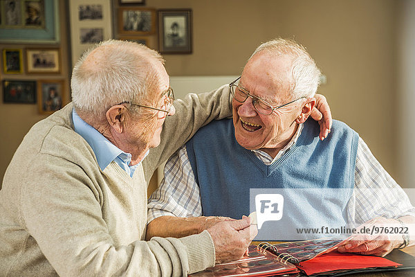 Zwei glückliche Seniorenfreunde mit Münzalbum