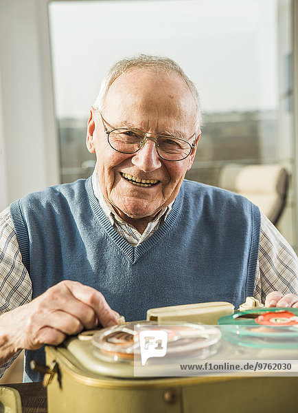 Smiling senior man operating old-fashioned recorder