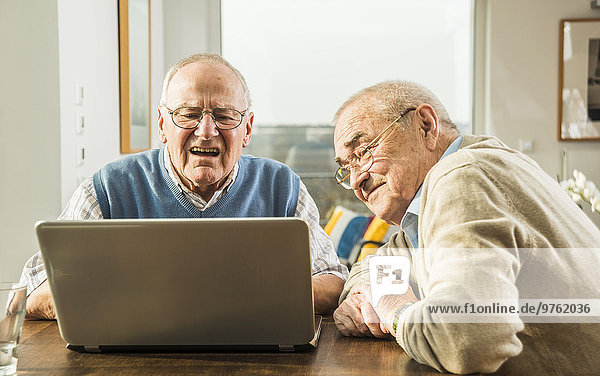 Two senior friends looking at laptop