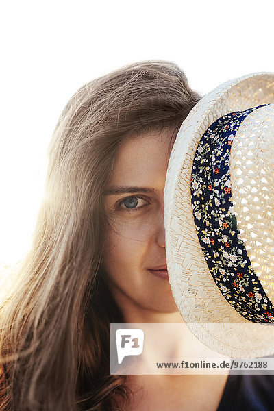 Woman hiding behind her summer hat