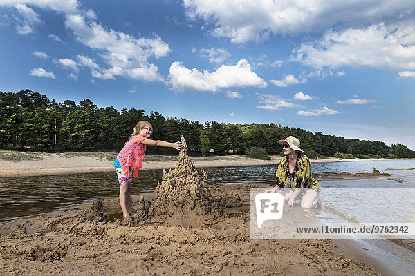 Estonia  Lake Peipus  Kauksi beach  girl and mother building sandcastle