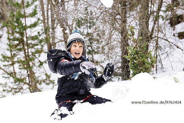Happy boy playing with snow in the woods
