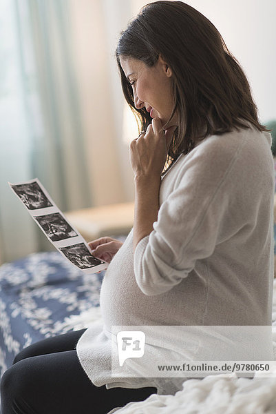 Pregnant woman watching ultrasound  sitting on bed