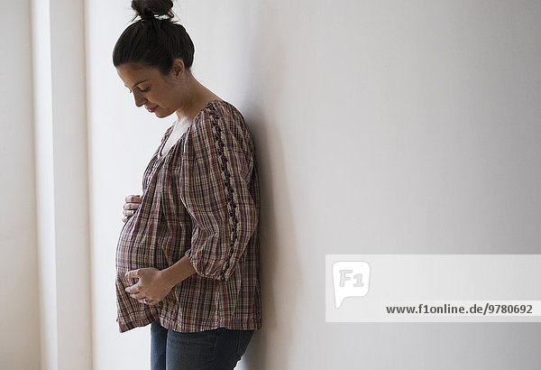 Pregnant woman leaning against wall