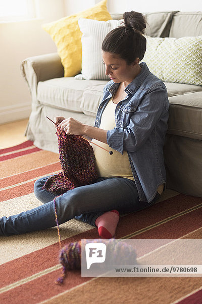 Pregnant woman sitting on floor knitting
