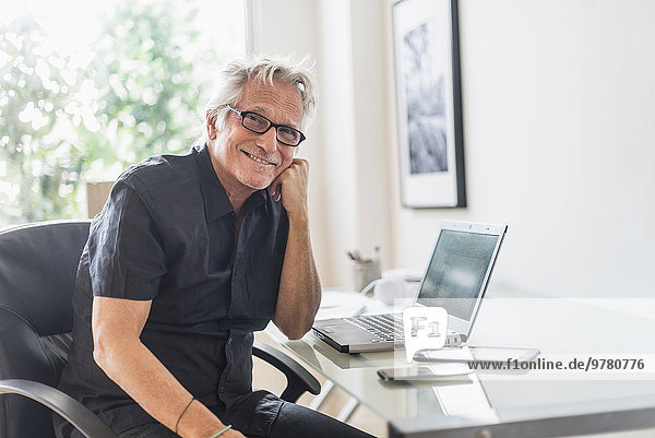 Portrait of smiling senior man sitting in home office