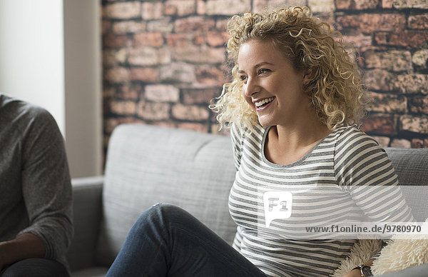 Blond woman laughing on sofa