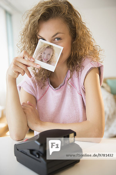Young woman holding Polaroid photo in front of her face