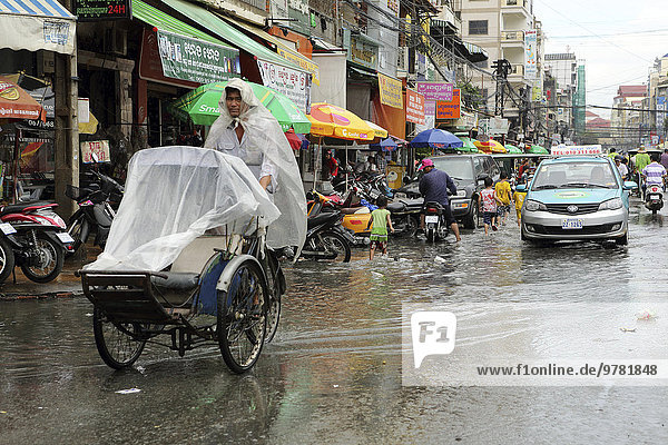 Traffice  including a cyclo and taxi  on a waterlogged street during the monsoon season in Phnom Penh  Cambodia  Indochina  Southeast Asia  Asia