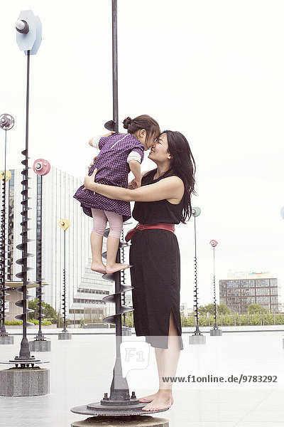 Mother and daughter nuzzling while standing on whimsical sculpture