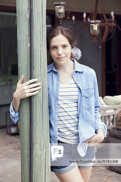 Young woman leaning against wooden post  portrait