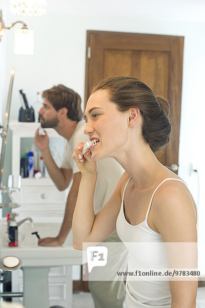 Woman brushing teeth  husband shaving