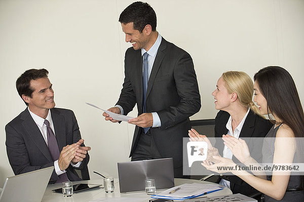 Executive receiving applause from colleagues during presentation