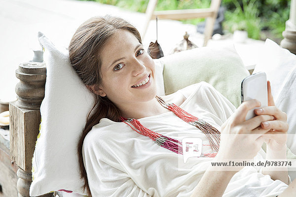 Young woman lying on back with smartphone in hands  portrait