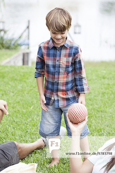 Junge beim Ballspielen im Seepark mit der Familie