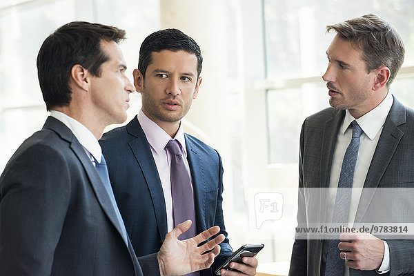 Businessmen standing together having serious discussion