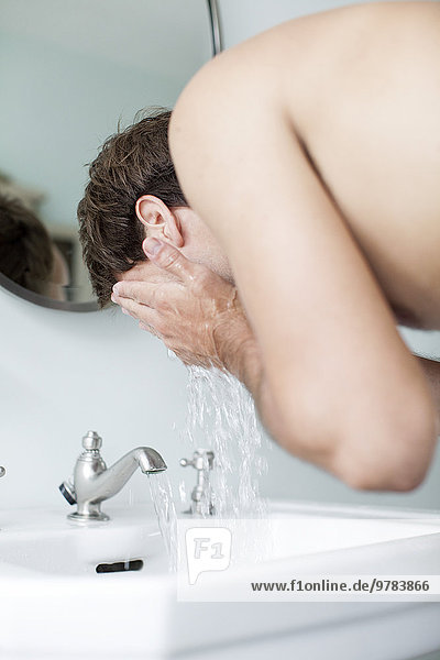 Mann wäscht Gesicht im Badezimmer Waschbecken