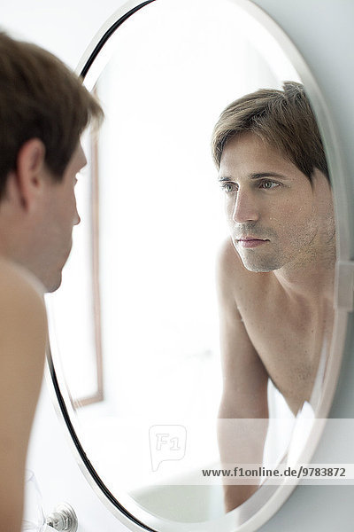Mann schaut sich selbst im Spiegel an