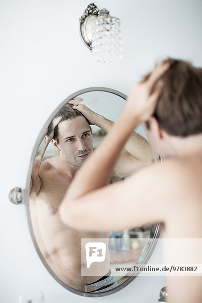 Mann untersucht Haaransatz im Spiegel