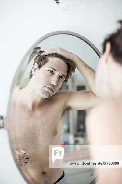 Mann untersucht Haaransatz im Spiegel