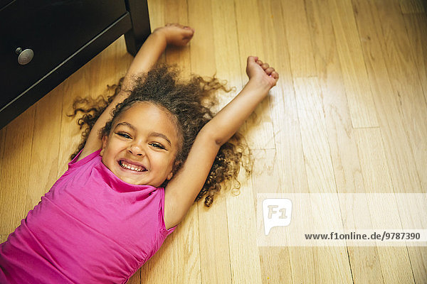 Mixed race girl smiling on wooden floor