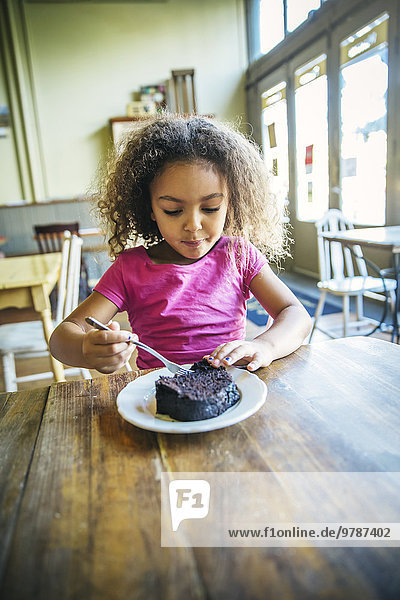 Mixed race girl eating dessert in cafe