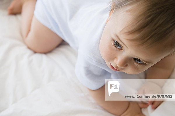 Close up of mixed race baby crawling on bed
