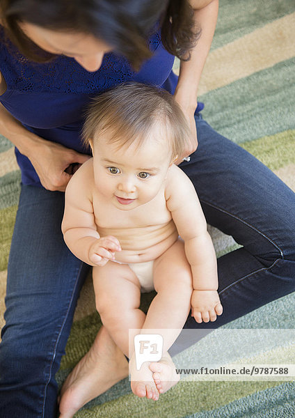 High angle view of mixed race mother playing with baby on floor