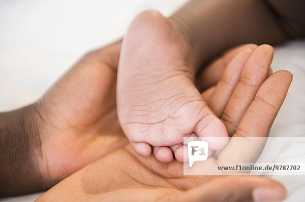 Close up of Black mother holding foot of baby