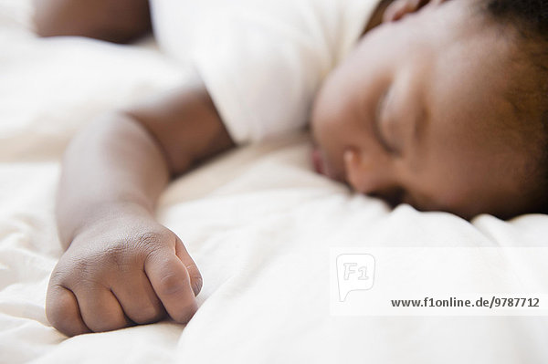Close up of Black baby boy sleeping on bed
