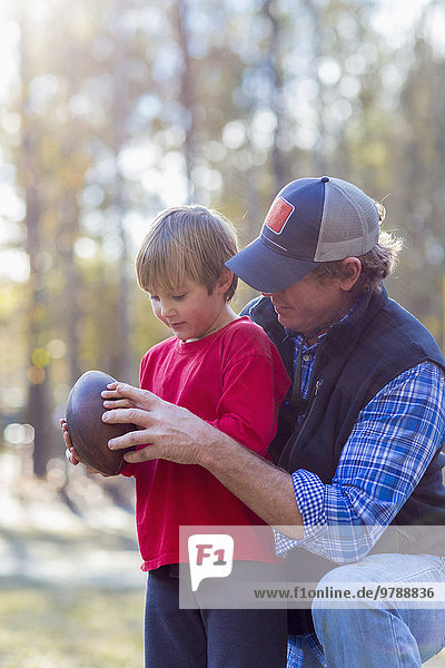 Caucasian father teaching son to play football