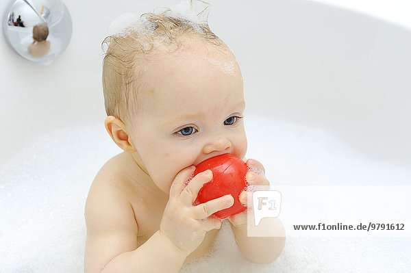 Baby girl  11 months  while bathing  playing with a ball  Germany  Europe