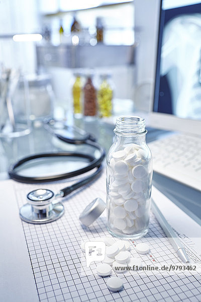 Flasche mit weißen Pillen  Karton und Stethoskop auf Schreibtisch