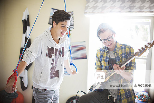 Zwei Teenager, die Spaß haben und E-Gitarre im Zimmer spielen.