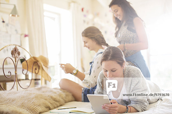 Three teenage girls relaxing in bedroom