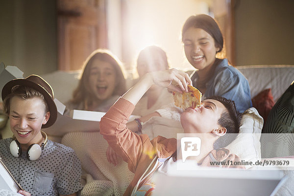 Gruppe von Teenagern beim Pizzaessen auf dem Sofa im Wohnzimmer