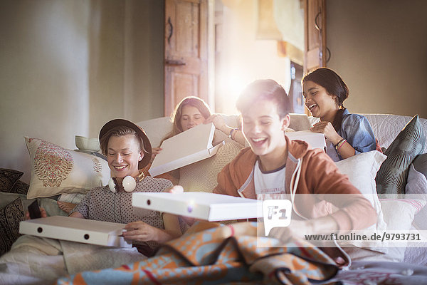 Gruppe von Teenagern öffnet Pizzakartons auf dem Sofa im Wohnzimmer