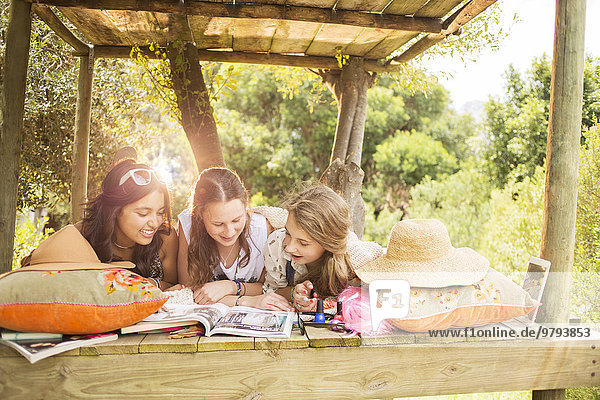 Drei Teenager-Mädchen beim Lesen im Sommer im Baumhaus