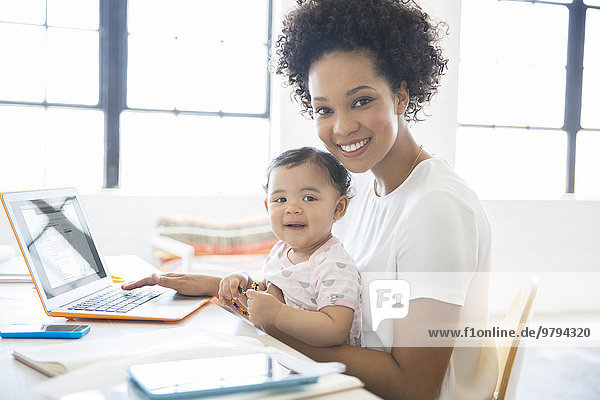 Mother working from home with daughter sitting on her lap