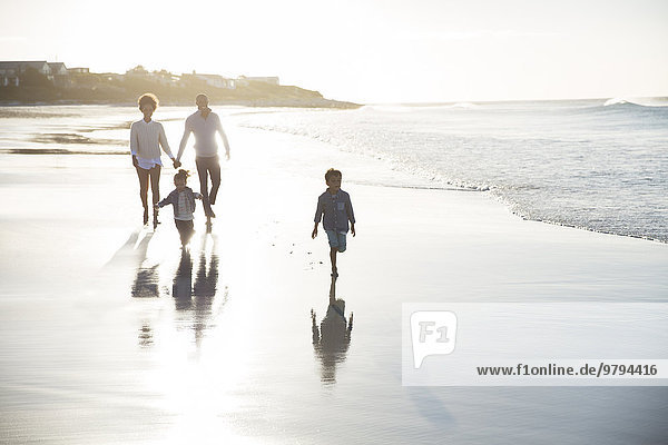 Family walking on beach at sunset