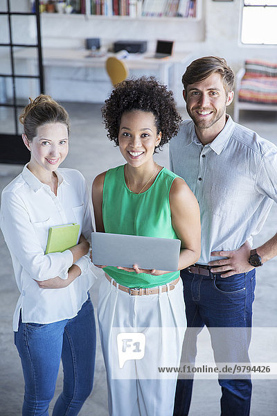 Portrait of three young people standing with digital tablet in studio